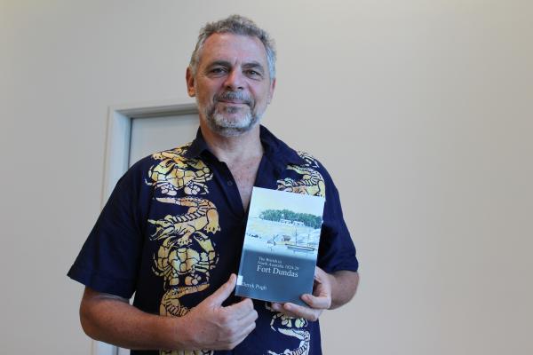 Man wearing short sleeve button up shirt holding a book that he submitted to the 2018 Award