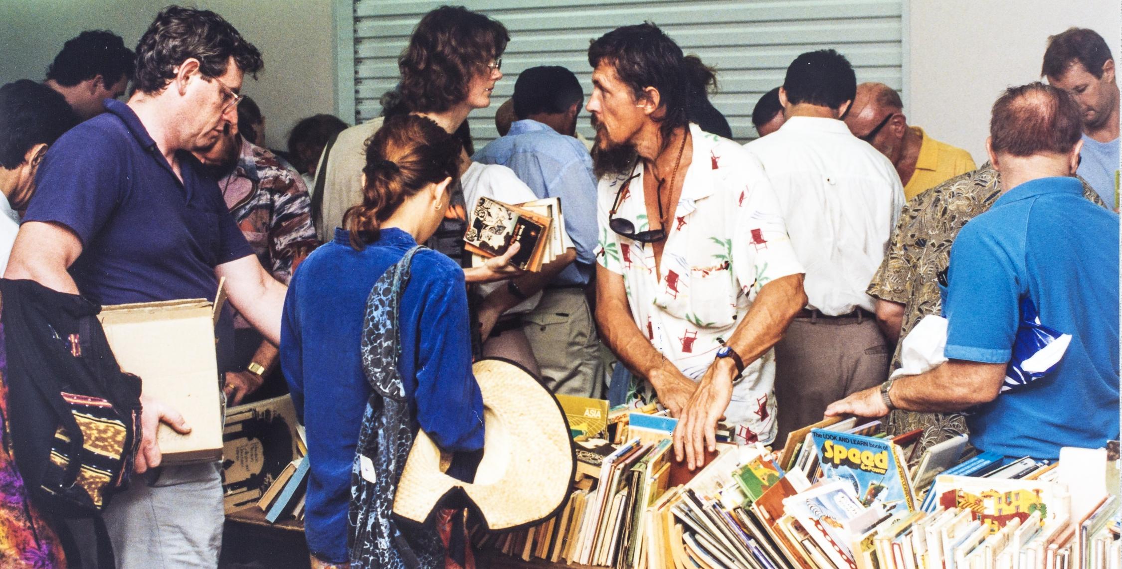 Gathering of people around a table of books that are for sale