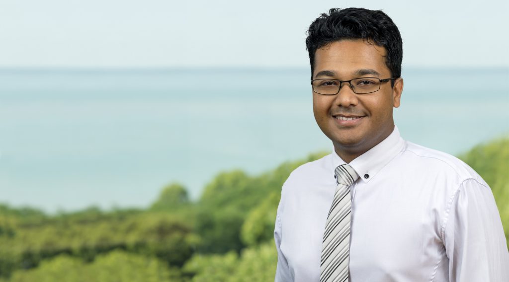 Kevin Kadirgamar looking into the camera and standing in front of ocean setting