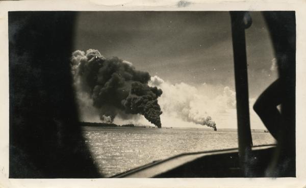The boat 'Zealandia' smoking after bombing. Smoke from 'Neptuna' and 'Barossa'.