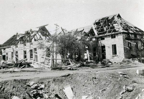 Parts of BAT, cable station, telegraph offices and Darwin Post Office buildings destroyed in the first Japanese air raids on 19 February 1942, showing one of the bomb craters in the foreground.